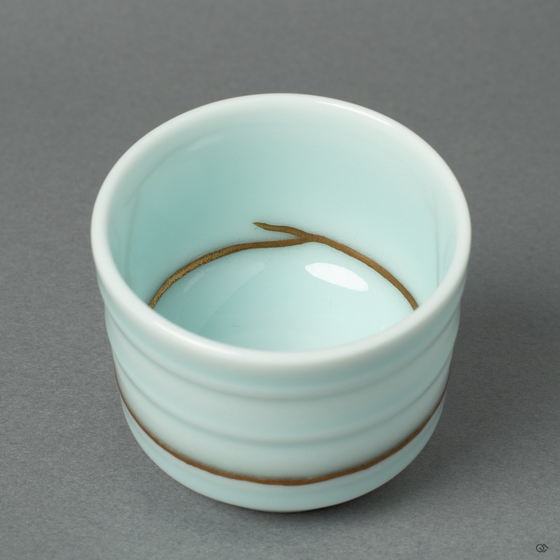 A detailed macro view of a 24k gold Kintsugi seam on the Arita ware porcelain. This close-up reveals the meticulous application of urushi lacquer and rich gold powder.