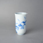 Kintsugi sake cup in Arita porcelain showing the vine of round blue leaves, rejoined with natural urushi, the 24K gold seam reaching the rim, side view.