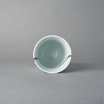 Kintsugi sake cup in Arita porcelain from above, rejoined with natural urushi, the 24K gold seam touching the rim twice and curving inside, top view.