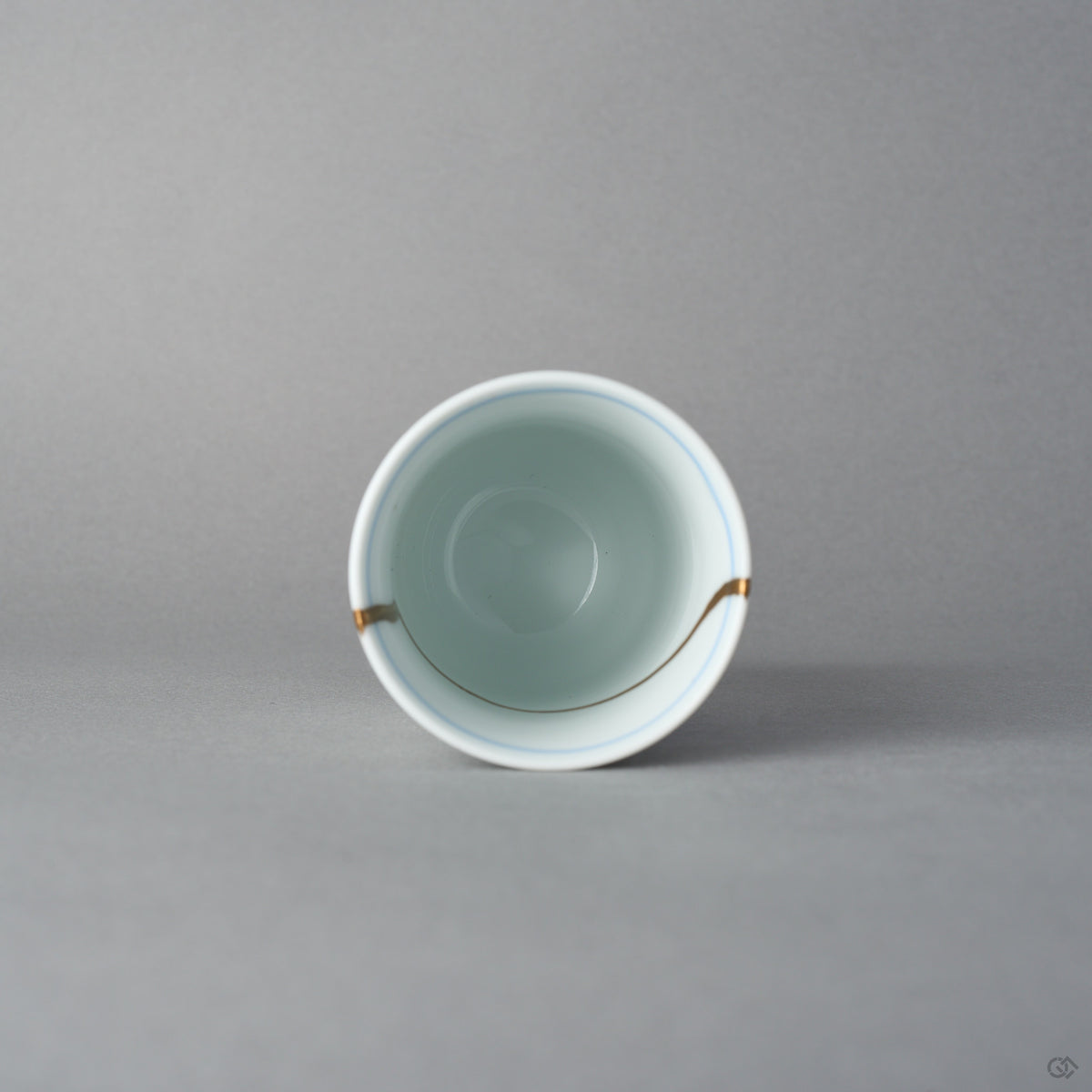 Kintsugi sake cup in Arita porcelain from above, rejoined with natural urushi, the 24K gold seam touching the rim twice and curving inside, top view.