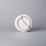 Kintsugi sake cup base seen from below, a natural urushi and 24K gold line crossing the foot ring and the white base of the Ko-Imari porcelain.