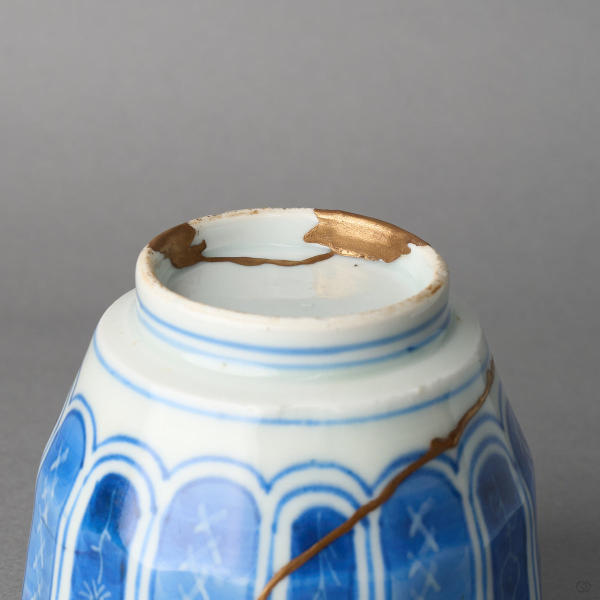 Kintsugi sake cup in Ko-Imari porcelain seen from below, rejoined with natural urushi, 24K gold filling a chip on the unglazed foot ring, detail view.