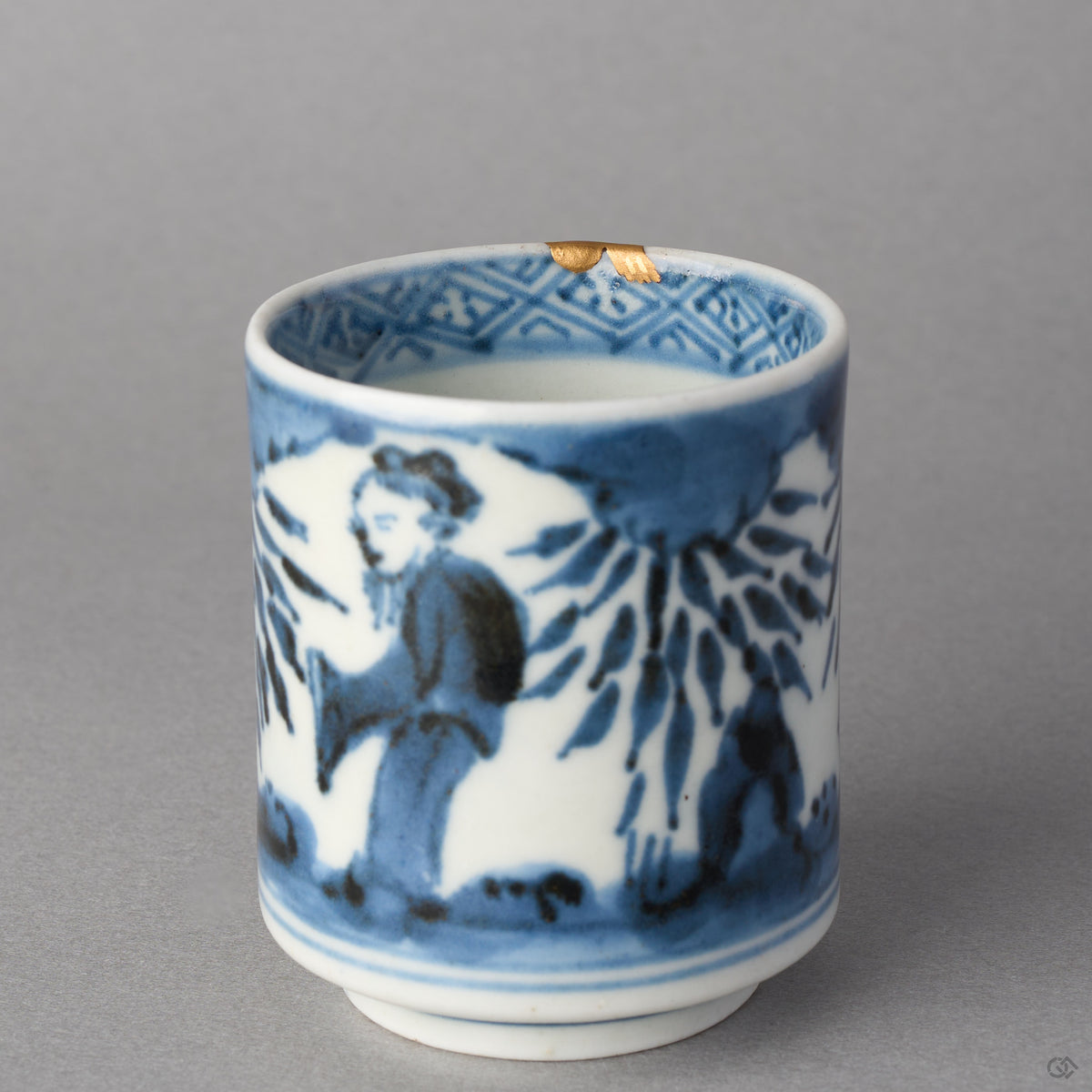 Kintsugi sake cup in Ko-Imari porcelain tilted to show the lattice band inside the rim, the natural urushi ground of the chip capped in 24K gold, close-up.