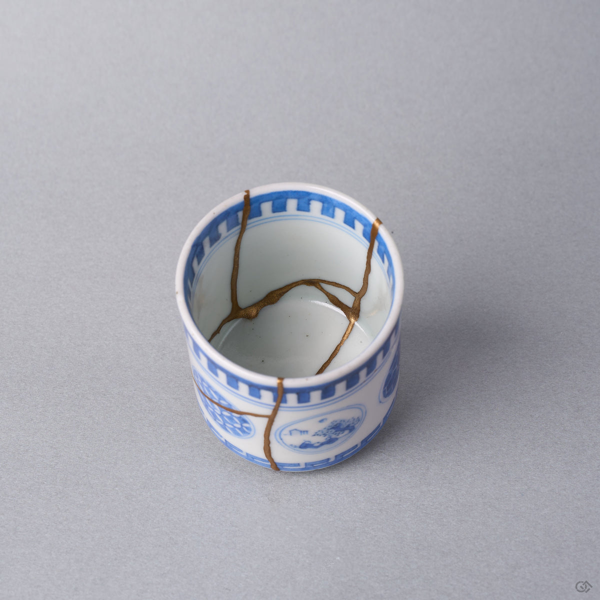 Kintsugi sake cup interior where three natural urushi and 24K gold lines meet at the center of the white well of the Ko-Imari porcelain.