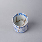Kintsugi sake cup interior where three natural urushi and 24K gold lines meet at the center of the white well of the Ko-Imari porcelain.