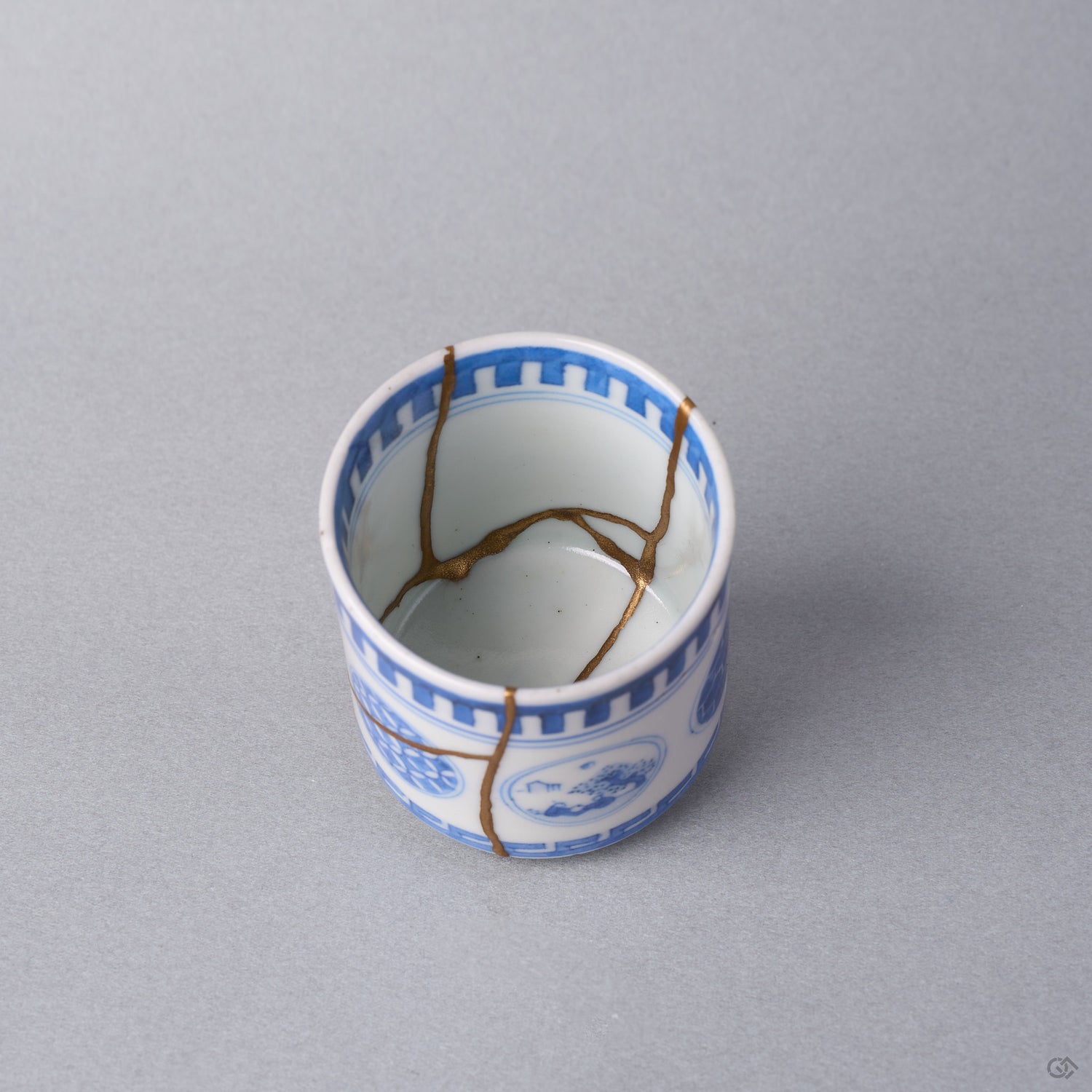 Kintsugi sake cup interior where three natural urushi and 24K gold lines meet at the center of the white well of the Ko-Imari porcelain.