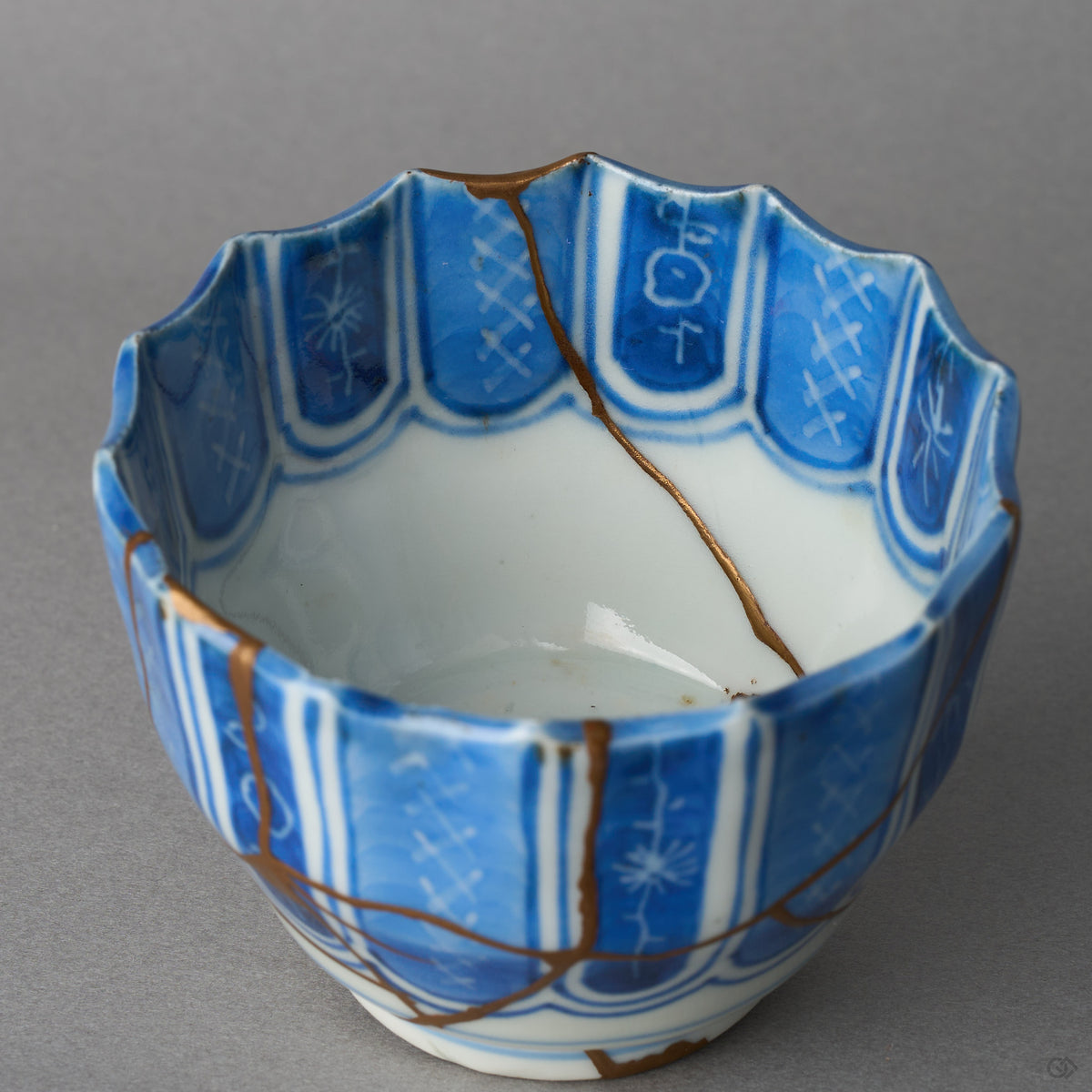 Kintsugi sake cup in Ko-Imari porcelain, rejoined with natural urushi, one 24K gold seam running from the rim down the inner wall into the well, interior view.