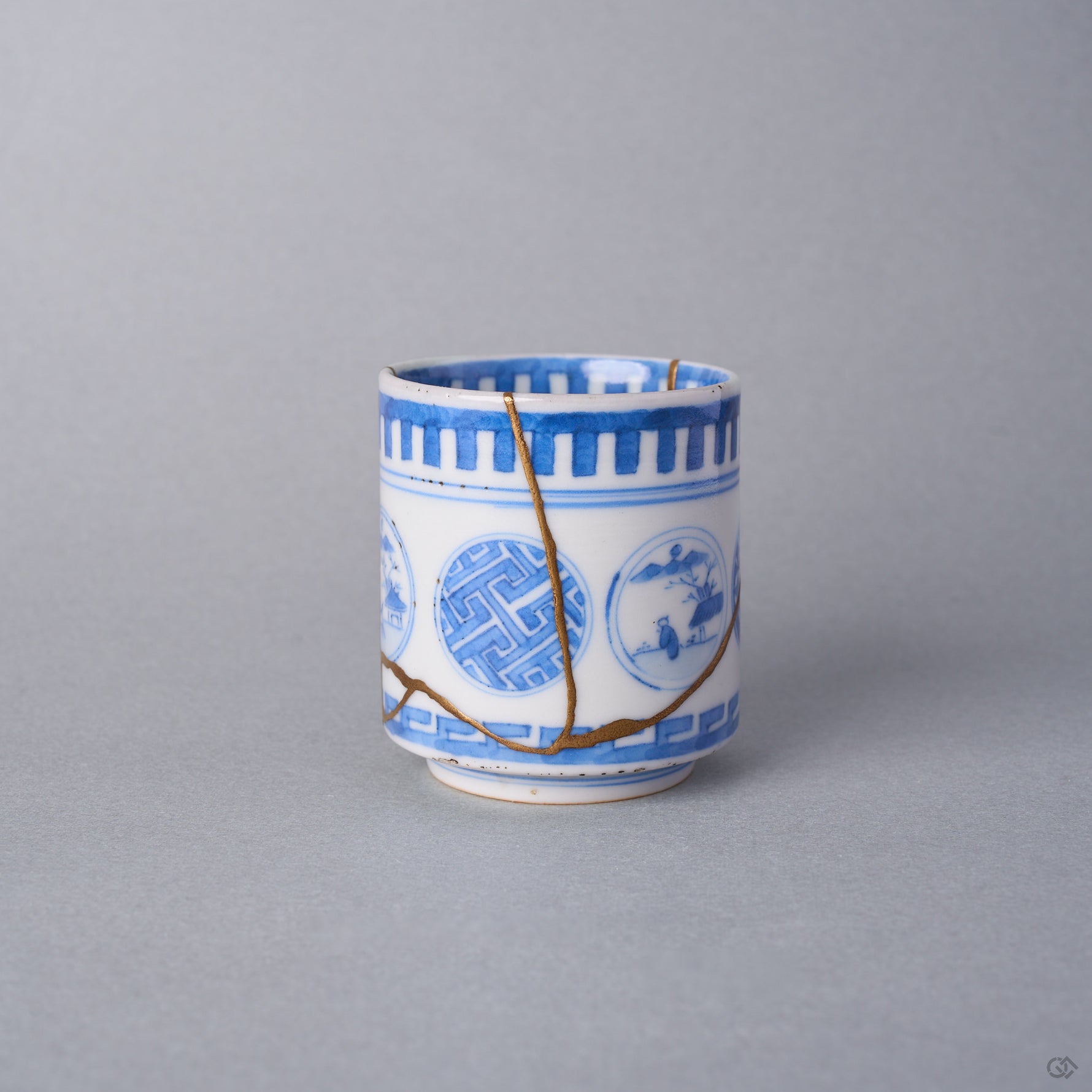 Kintsugi sake cup side view, a natural urushi and 24K gold seam descending through the sayagata window of the Ko-Imari porcelain and branching at the lower cup.