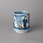 Kintsugi sake cup in Ko-Imari porcelain from the side, two urushi-e sparrows beneath the cobalt bamboo, the natural urushi and 24K gold rim at the edge.
