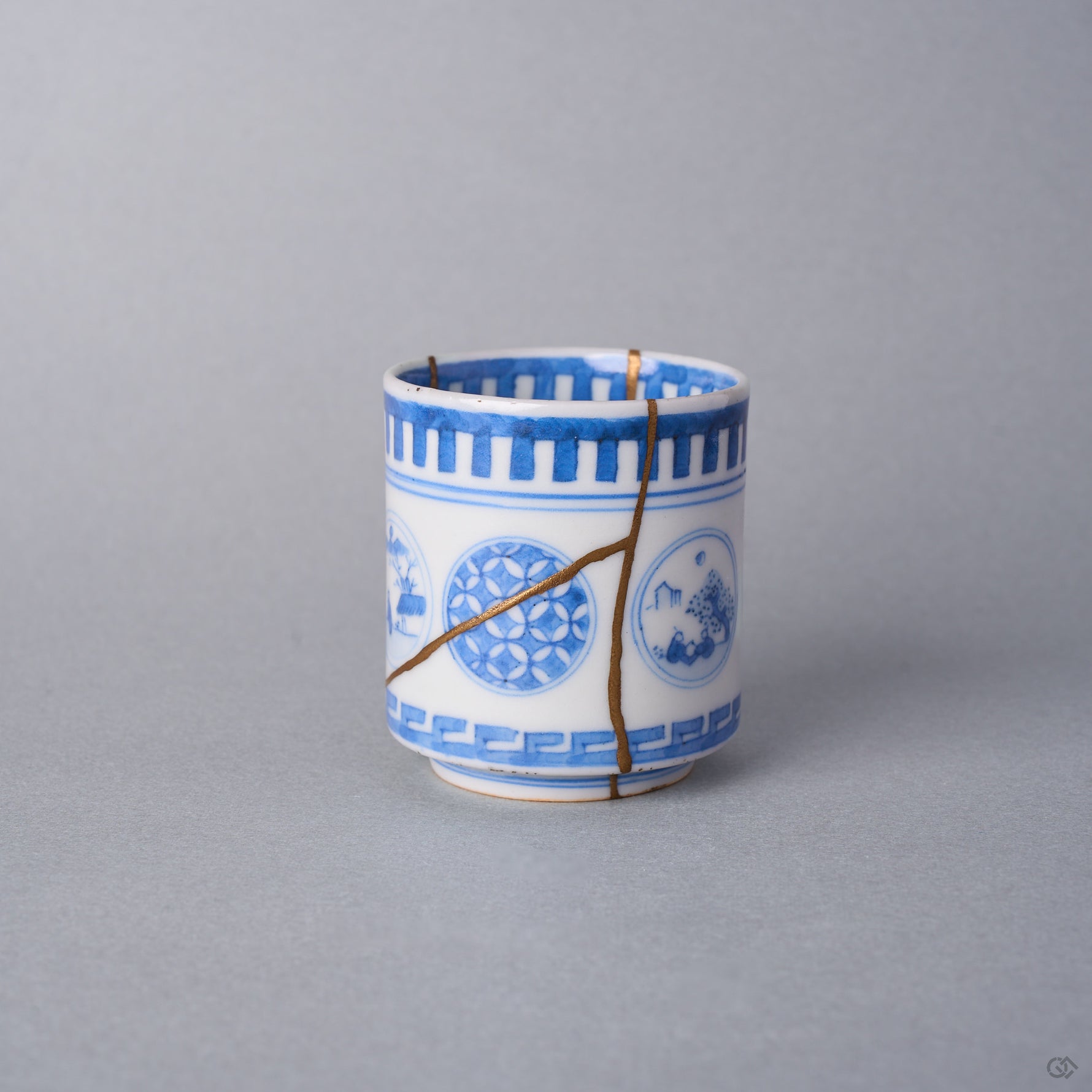 Kintsugi sake cup side view with natural urushi and 24K gold lines crossing the shippo window of the Ko-Imari sometsuke porcelain in a Y shape.