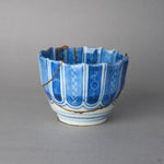 Kintsugi sake cup in blue-and-white Ko-Imari porcelain, rejoined with natural urushi, a 24K gold seam circling the base below the columns, side view.