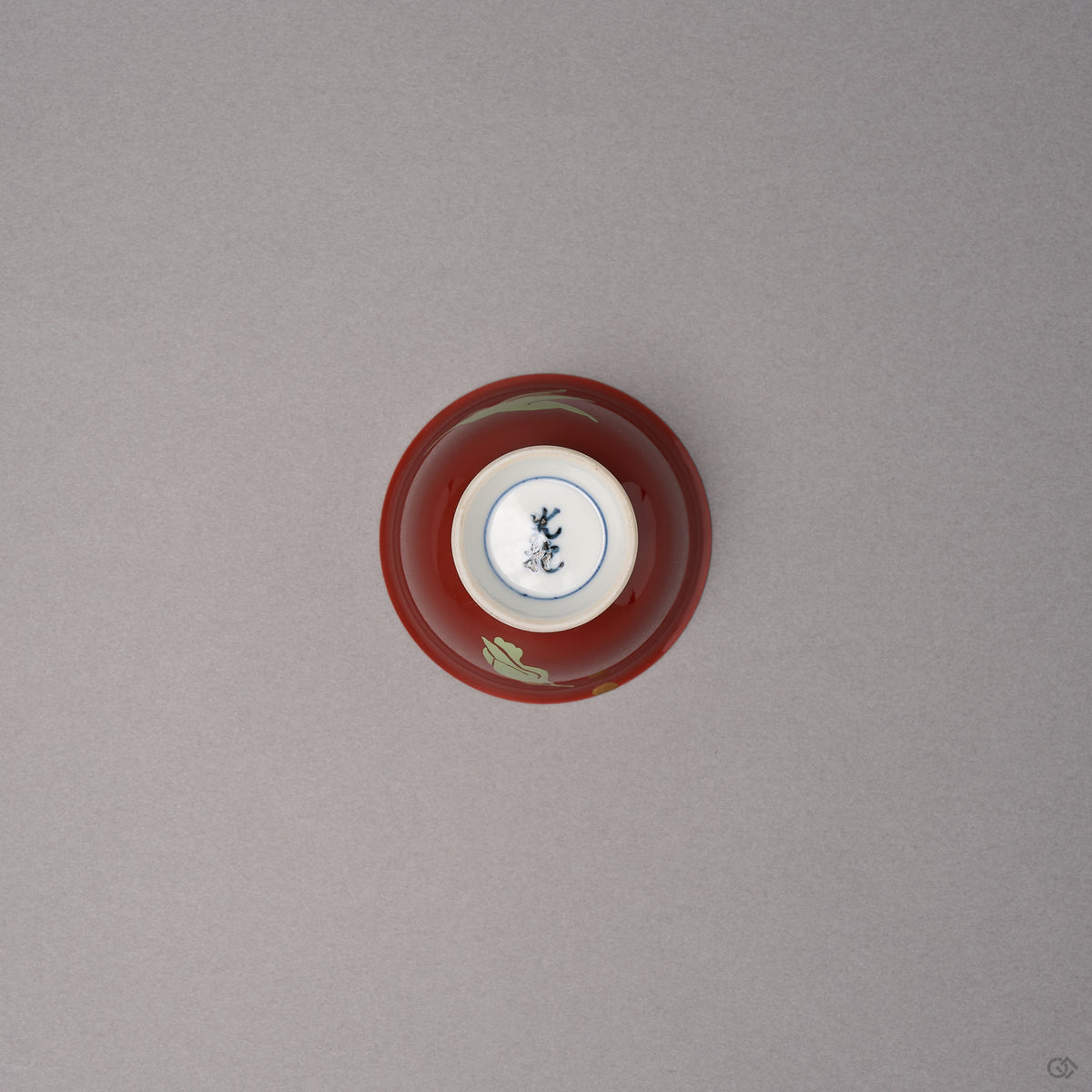 Kintsugi sake cup in red Kyoto ware porcelain seen from below, the white foot with a blue kiln mark and urushi-painted bird tips at the edge, bottom view.