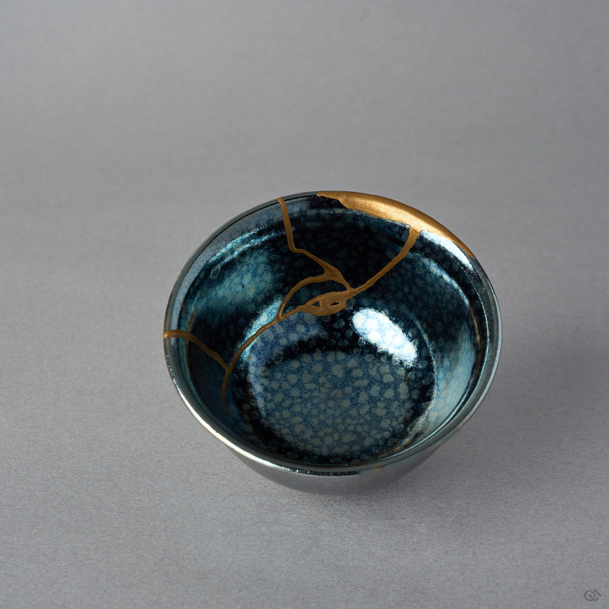 Kintsugi sake cup interior in Kyoto ware tenmoku glaze, rejoined with natural urushi, three 24K gold lines converging on a broad gold crescent along the rim.
