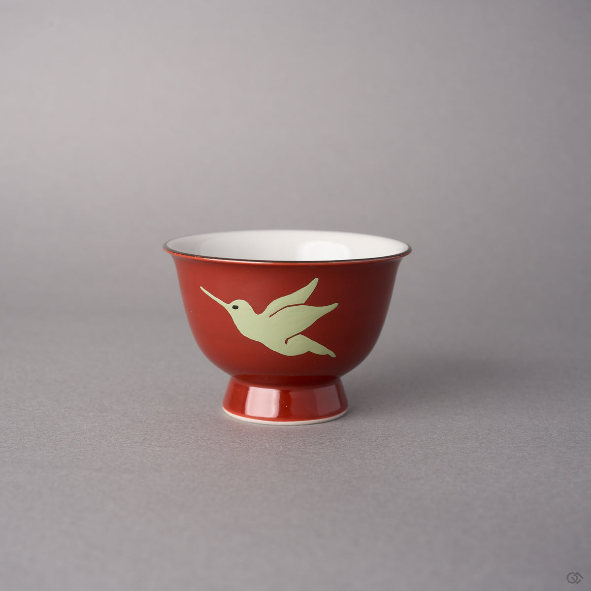 Kintsugi sake cup in red Kyoto ware porcelain restored with natural urushi, the second hummingbird in flight painted in pale urushi, side view.