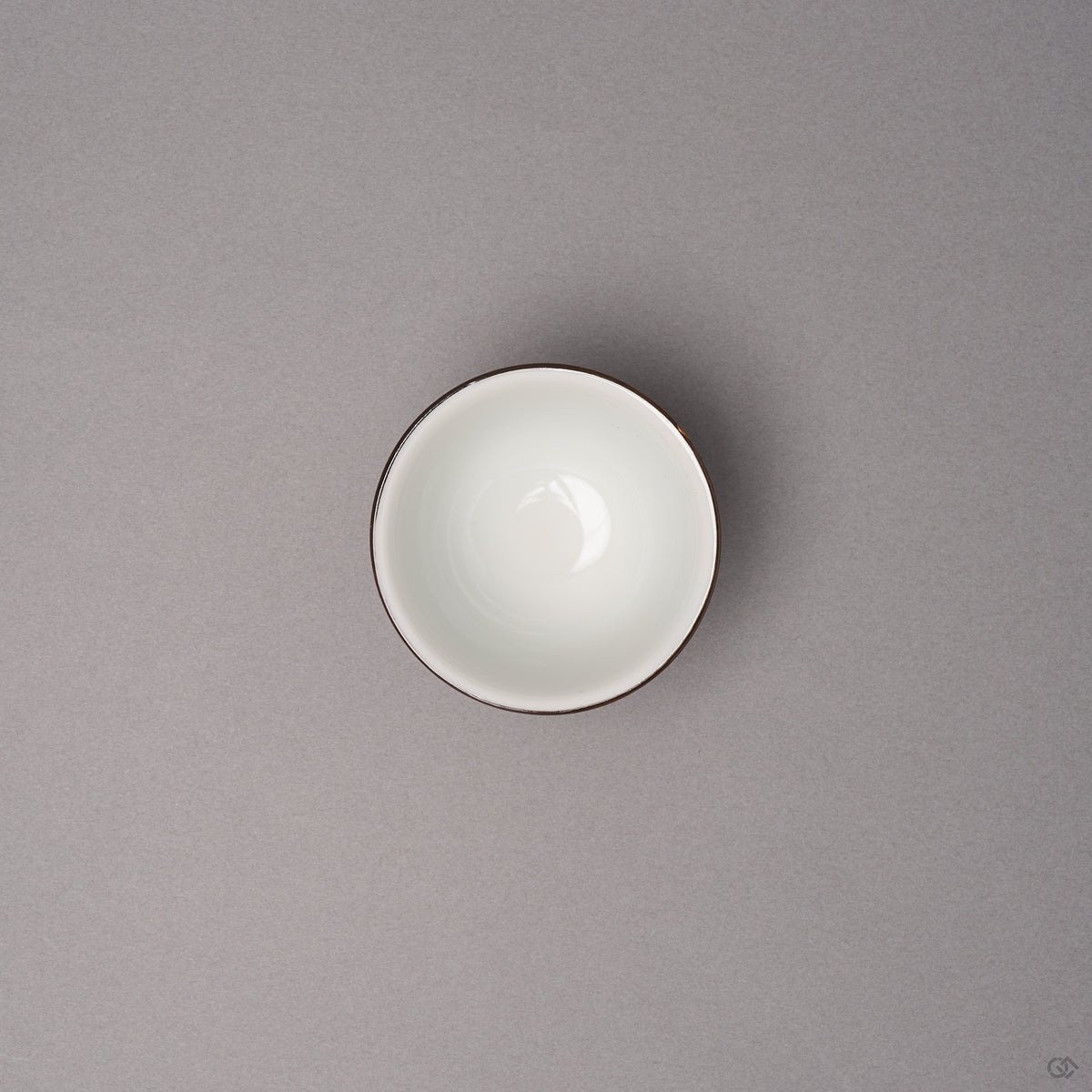 Kintsugi sake cup in Kyoto ware porcelain seen from above, the white interior and dark rim line visible, restored with natural urushi, top view.