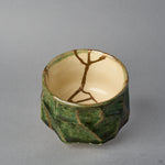 Kintsugi sake cup interior in Oribe ware, natural urushi and 24K gold lines branching from the rim across the ivory well to meet at its center.