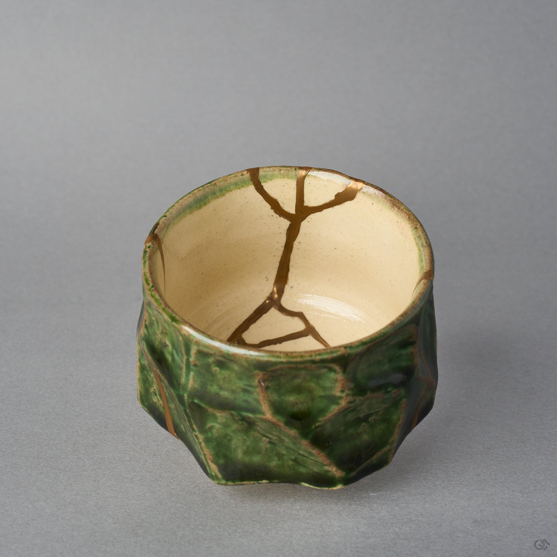 Kintsugi sake cup interior in Oribe ware, natural urushi and 24K gold lines branching from the rim across the ivory well to meet at its center.