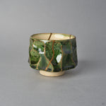 Kintsugi sake cup in Oribe green pottery seen from the side, one natural urushi and 24K gold line running straight down the faceted wall from rim to foot.
