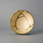 Kintsugi sake cup in Oribe ware seen from directly above, natural urushi and 24K gold lines branching across the ivory well within the green rim, top view.