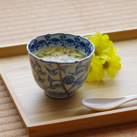 A photo of an authentic Kintsugi pottery piece being used in a real-world setting, such as a cup of soup being poured into a Kintsugi cup