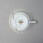 Kintsugi tea cup in Early Noritake porcelain, seen from below: the backstamp sits on the foot and the 24K gold urushi seam crosses the body beside it.