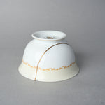 Kintsugi tea cup in Early Noritake porcelain, inverted side view: the 24K gold line in natural urushi arcs over the body and the gilt scroll band.