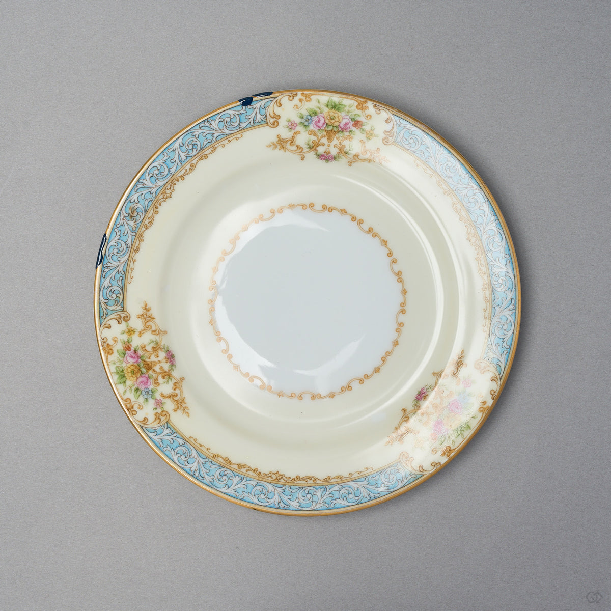 Kintsugi tea cup set saucer in Early Noritake porcelain, seen from above: two rim chips restored in blue natural urushi by the turquoise border.