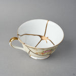 Kintsugi tea cup interior in Early Noritake porcelain, natural urushi and 24K gold seams converging into a star at the center of the white well, close-up.