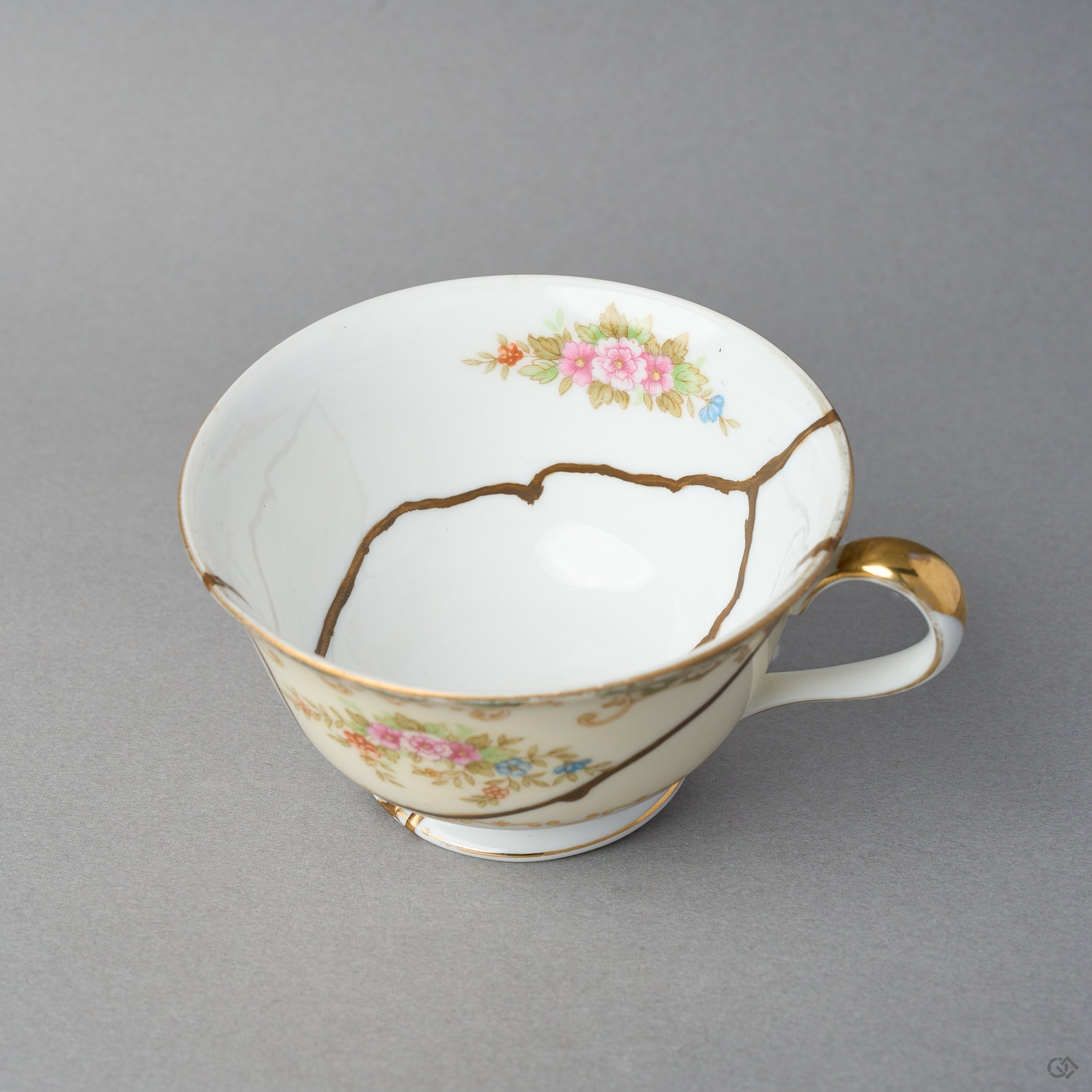 Kintsugi tea cup in Early Noritake porcelain tilted to show the well, a natural urushi and 24K gold line crossing the interior beneath the painted roses.
