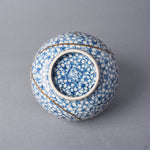 Kintsugi tea cup base with blossoms continuing under the foot around a blue kiln mark, urushi and 24K gold seams beside the foot ring.