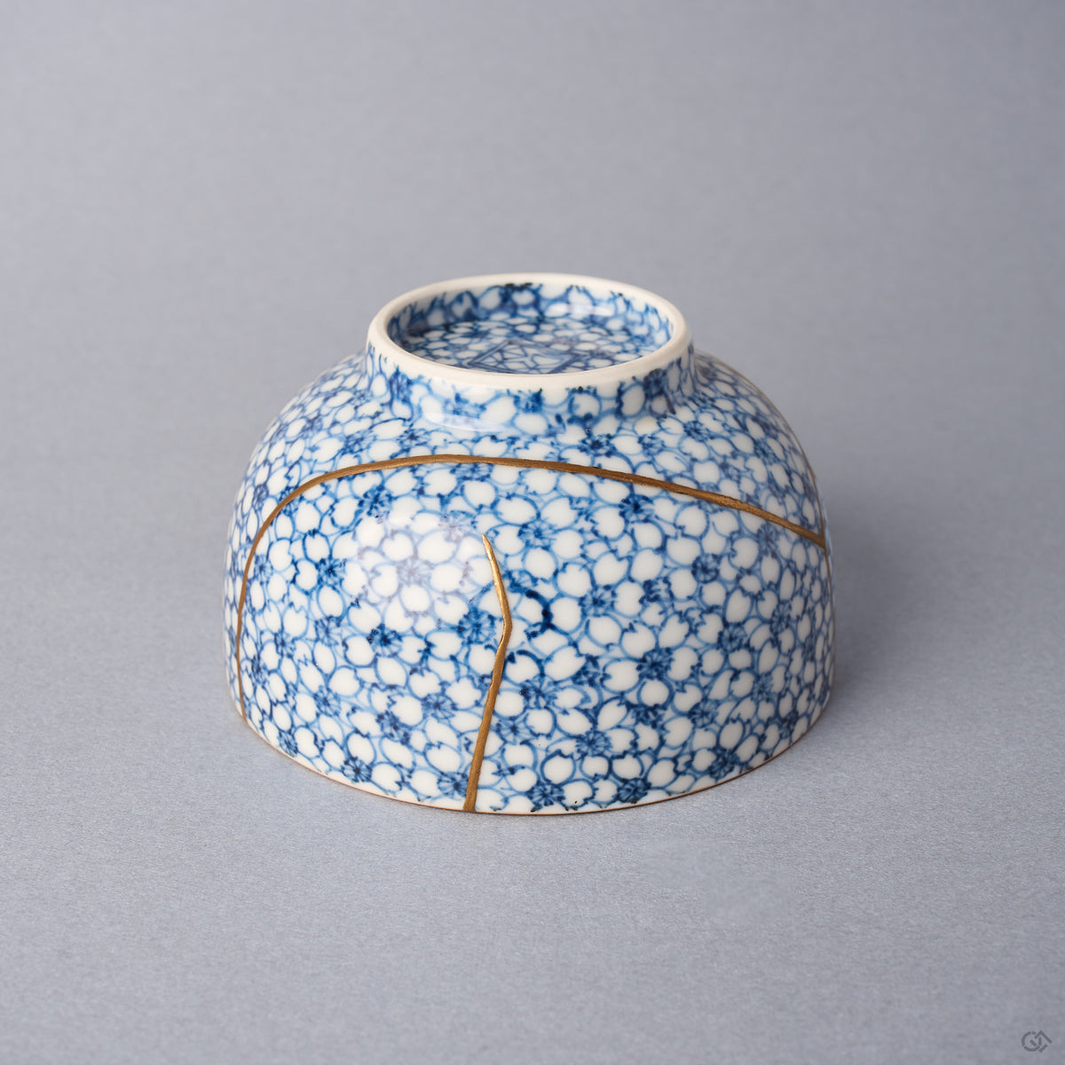 Kintsugi tea cup inverted from another side, an urushi and 24K gold line circling the lower body as a branching seam descends.