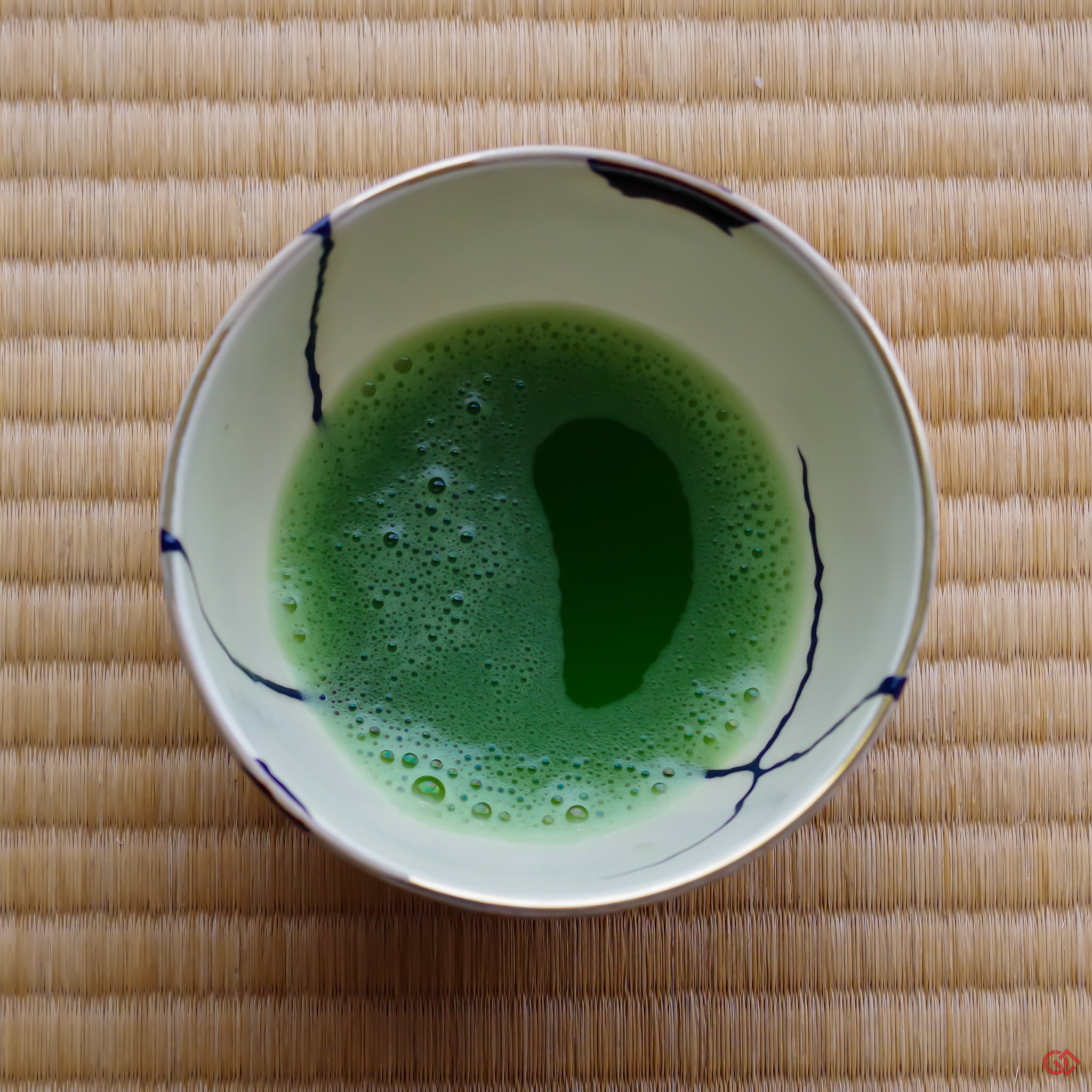 A photo of an authentic Kintsugi pottery piece being used in a real-world setting, such as a tea bowl of green tea being poured into a Kintsugi teabowl.