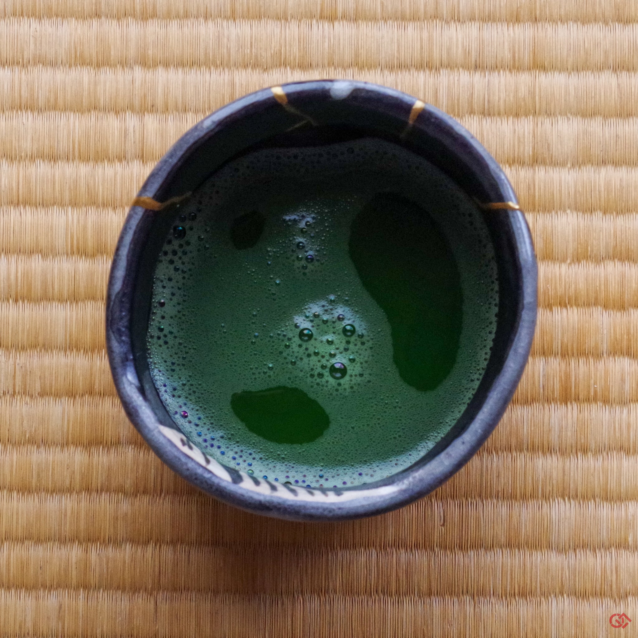 A photo of an authentic Kintsugi pottery piece being used in a real-world setting, such as a cup of matcha being poured into a Kintsugi teabowl.