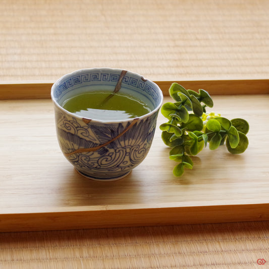 A photo of an authentic Kintsugi pottery piece being used in a real-world setting, such as a cup of green tea being poured into a Kintsugi cup
