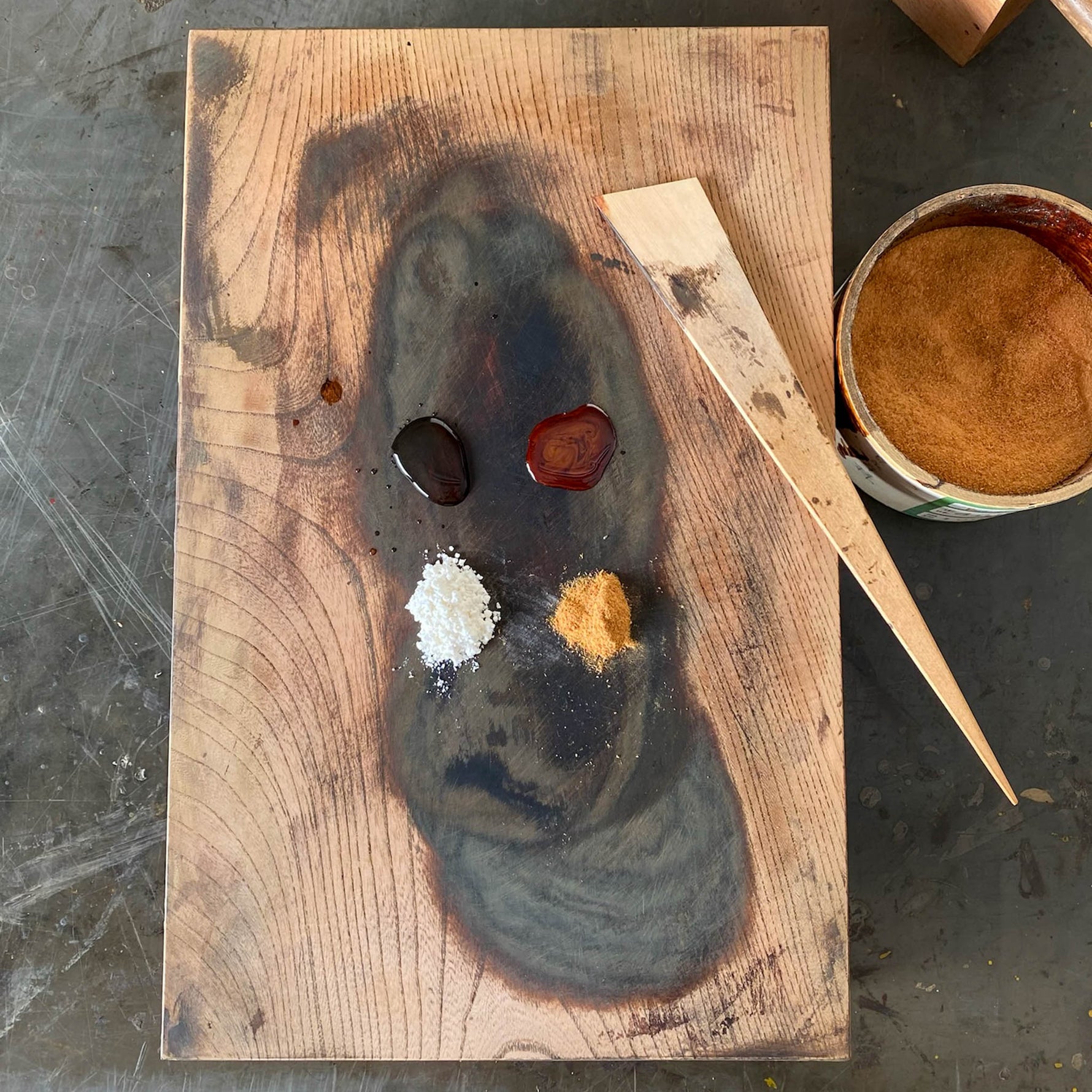 Kokuso-urushi lacquer putty made from raw urushi, water, wheat flour, and zelkova wood powder, displayed on a wooden board with a bamboo spatula for filling missing areas in kintsugi