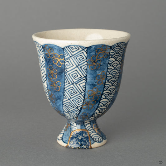 A Kyoto ware sake cup, where 24k gold Kintsugi and a textured Kawari-nuri Seigaiha wave pattern exist in quiet harmony.
