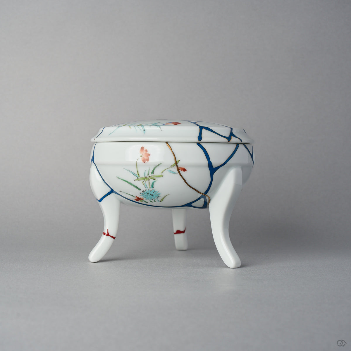 Close-up of the kintsugi area on the Arita bowl body seen from underneath, a blue urushi line edged in 24K gold running across the white porcelain toward a restored foot.