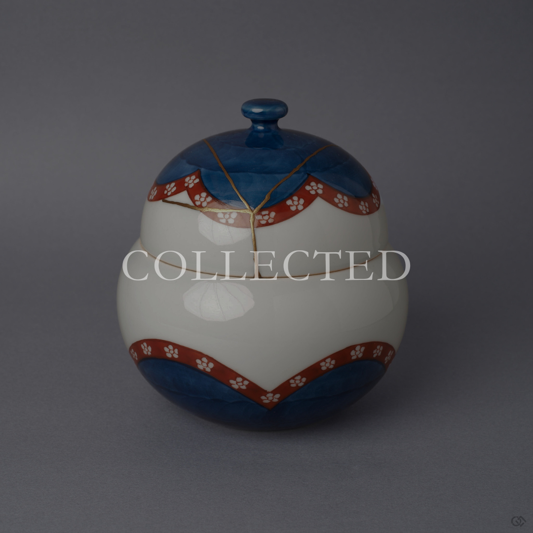 Arita ware lidded bowl in glossy white porcelain with a cobalt-blue crown and base, vermilion plum-blossom bands, and a 24K gold kintsugi seam over the domed lid, shown from the front. Sold out.