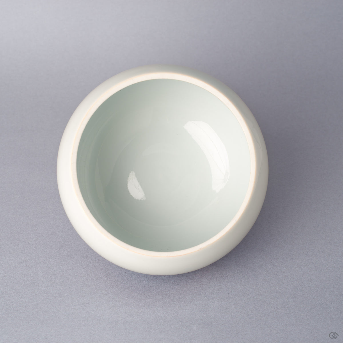 Top view of the body of an Arita ware lidded bowl in white porcelain with a pale celadon-toned glazed interior, glossy and undamaged, shown without the lid.