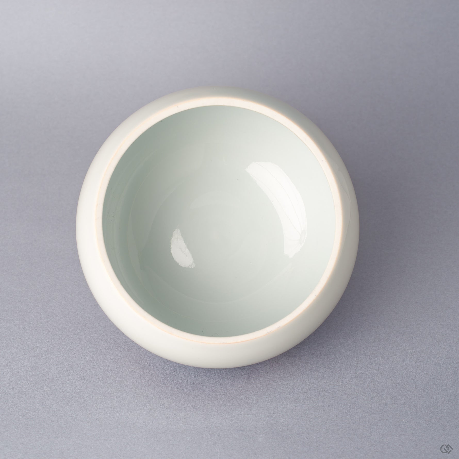 Top view of the body of an Arita ware lidded bowl in white porcelain with a pale celadon-toned glazed interior, glossy and undamaged, shown without the lid.