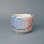 The blush-pink side of this rounded matcha bowl, a gold kintsugi seam following it, one-of-a-kind in glaze and restoration.