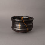 Side view of kintsugi Arita matcha bowl showing gold seams radiating across the robust porcelain form, embodying wabi-sabi simplicity.