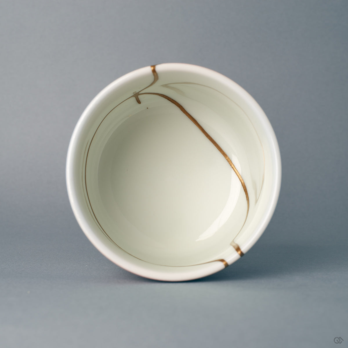 Seen from above, the round rim frames gold kintsugi lines reaching into the white interior — a moment of contemplation.
