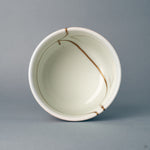Seen from above, the round rim frames gold kintsugi lines reaching into the white interior — a moment of contemplation.