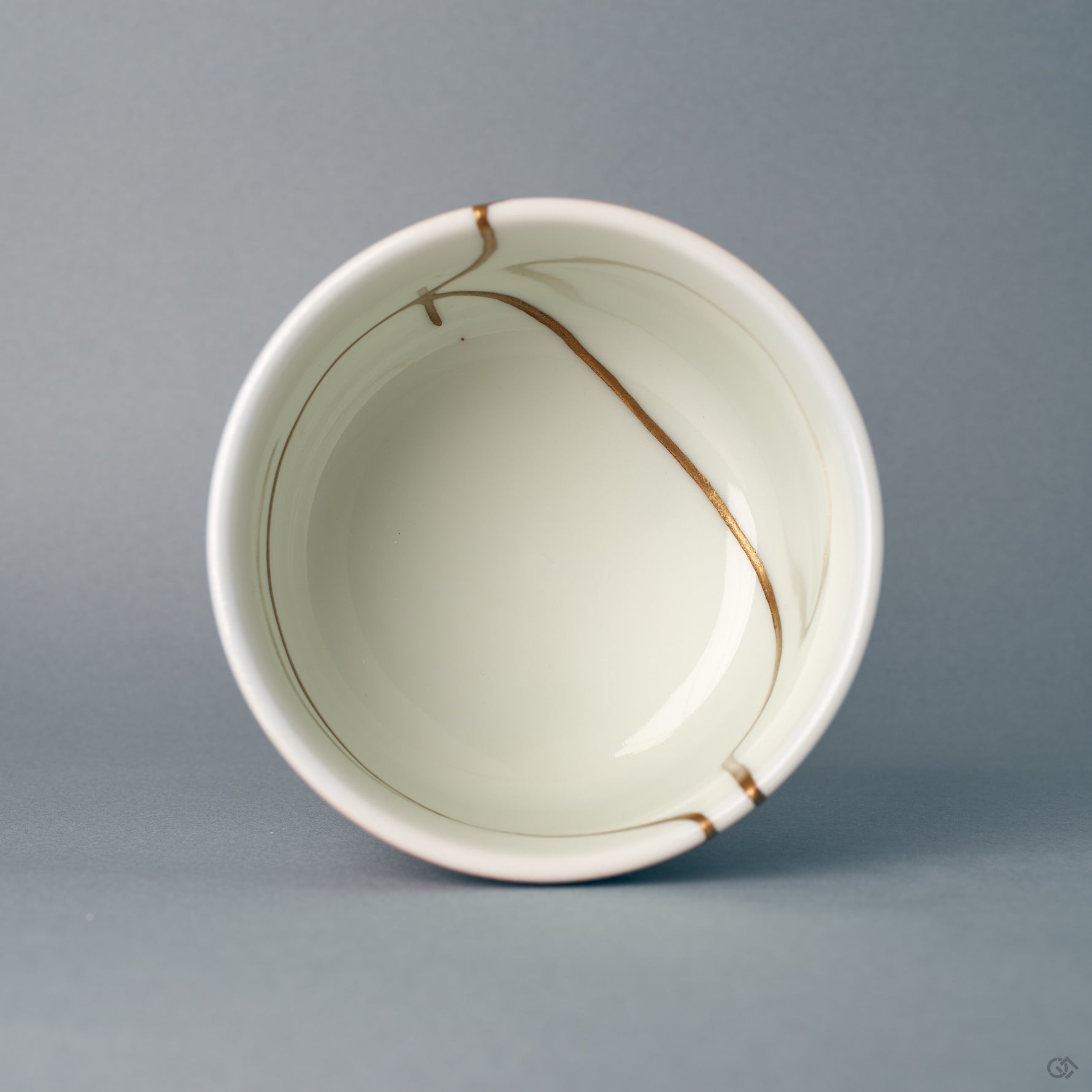 Seen from above, the round rim frames gold kintsugi lines reaching into the white interior — a moment of contemplation.