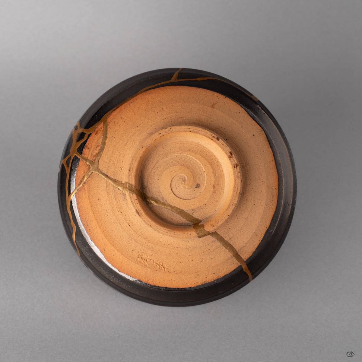 The foot ring of this Arita kintsugi bowl grounds the piece, dark glaze meeting bare clay, history made visible at the base.
