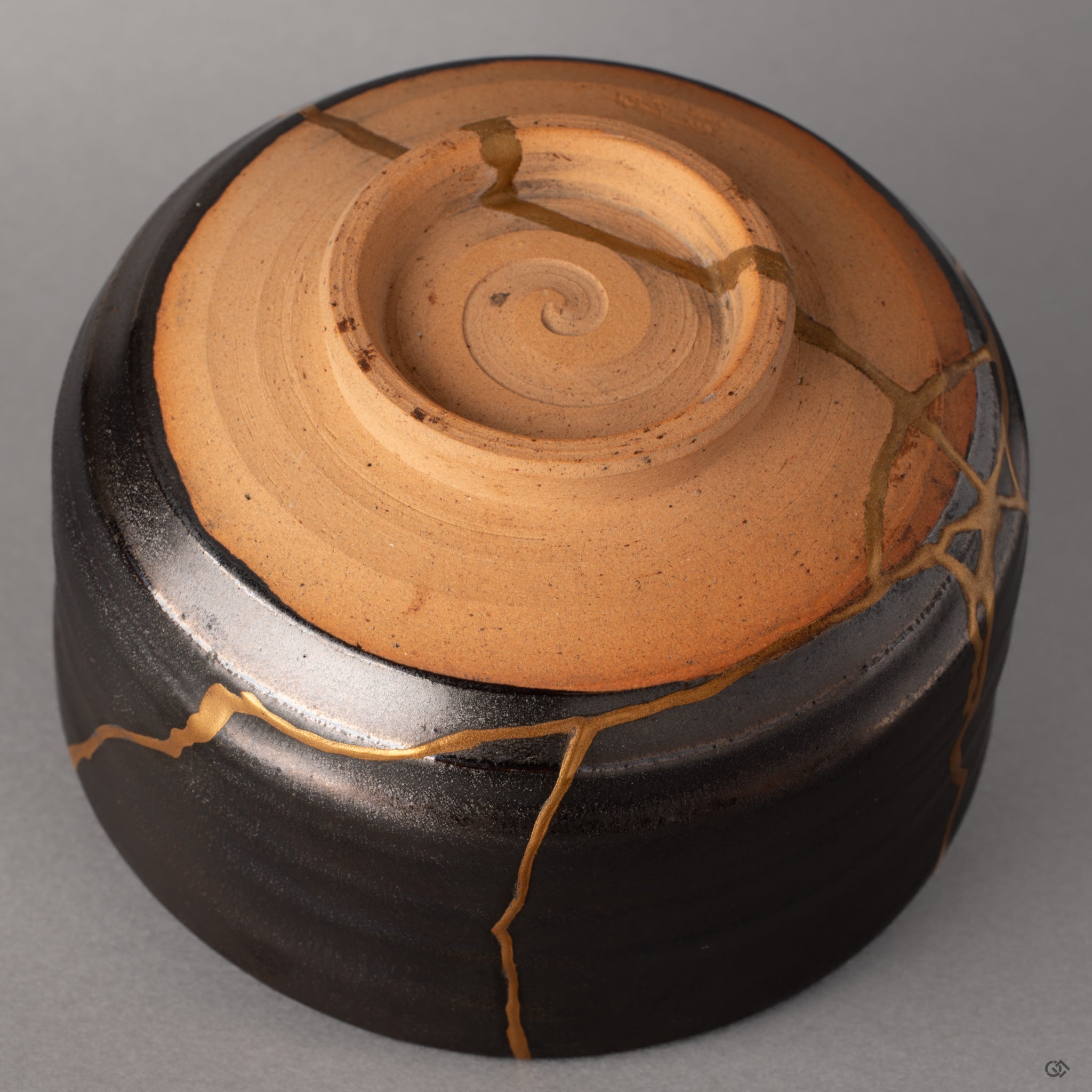 Light rests gently on the kintsugi seams of this Arita bowl, gold reflecting against dark porcelain, tactile history in view.