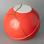 Close-up of the red glaze meeting the gold kintsugi seam, a tactile moment of visible resilience against the smooth surface.