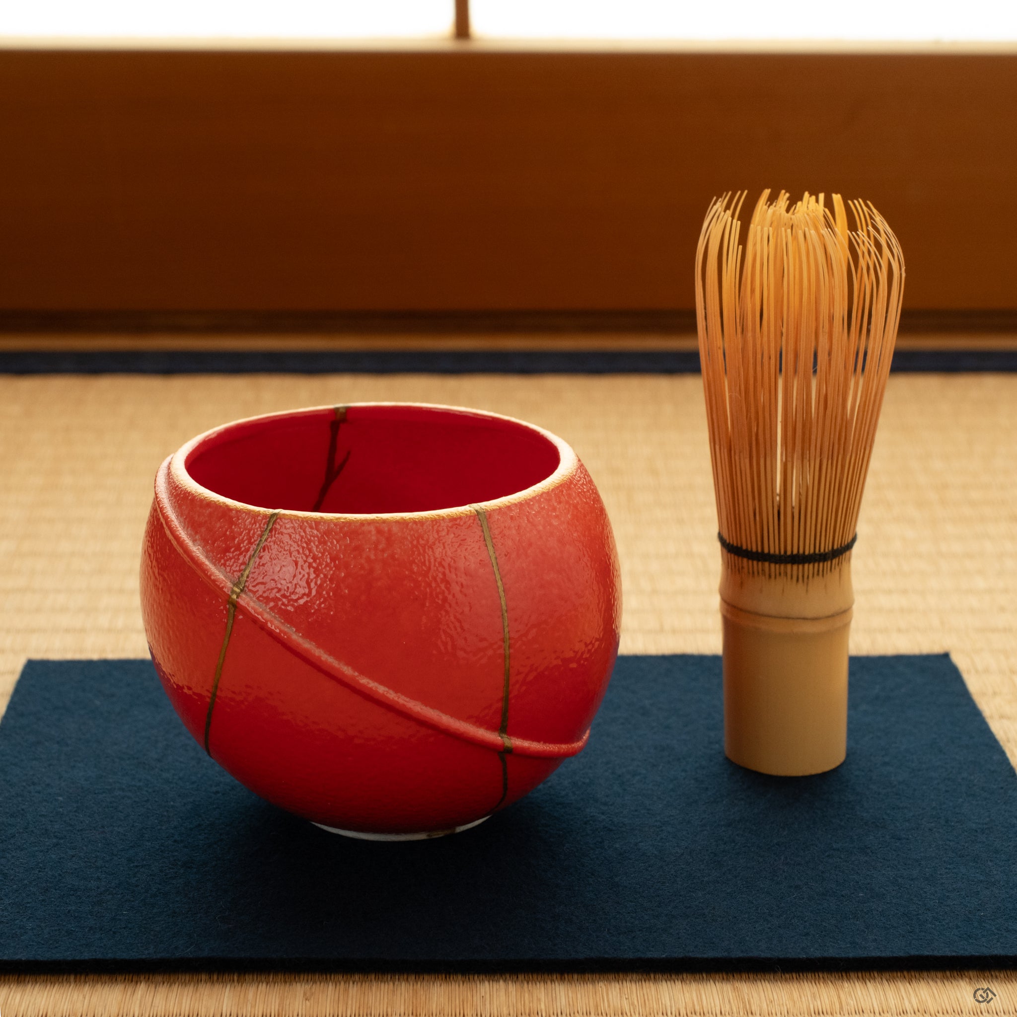 Matcha bowl rests on tatami, the gold kintsugi catching soft light and evoking a sense of mindful luxury in a quiet room.