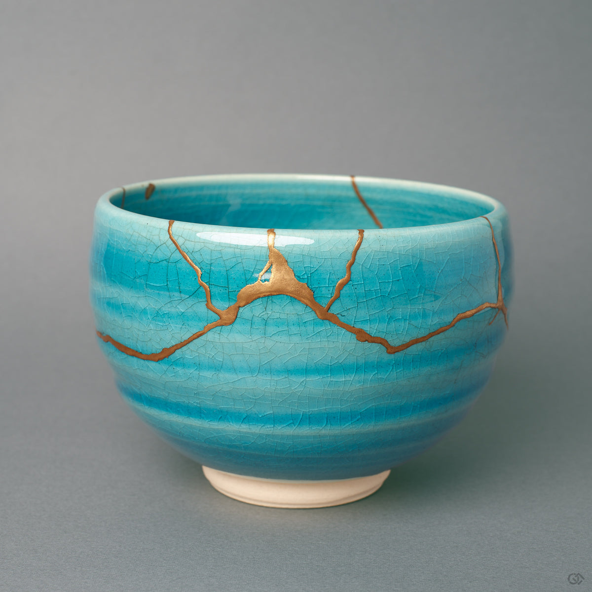 Kintsugi Kyoto matcha bowl in turquoise crackle glaze, gold seams crossing the front, wabi-sabi held in a single vessel.